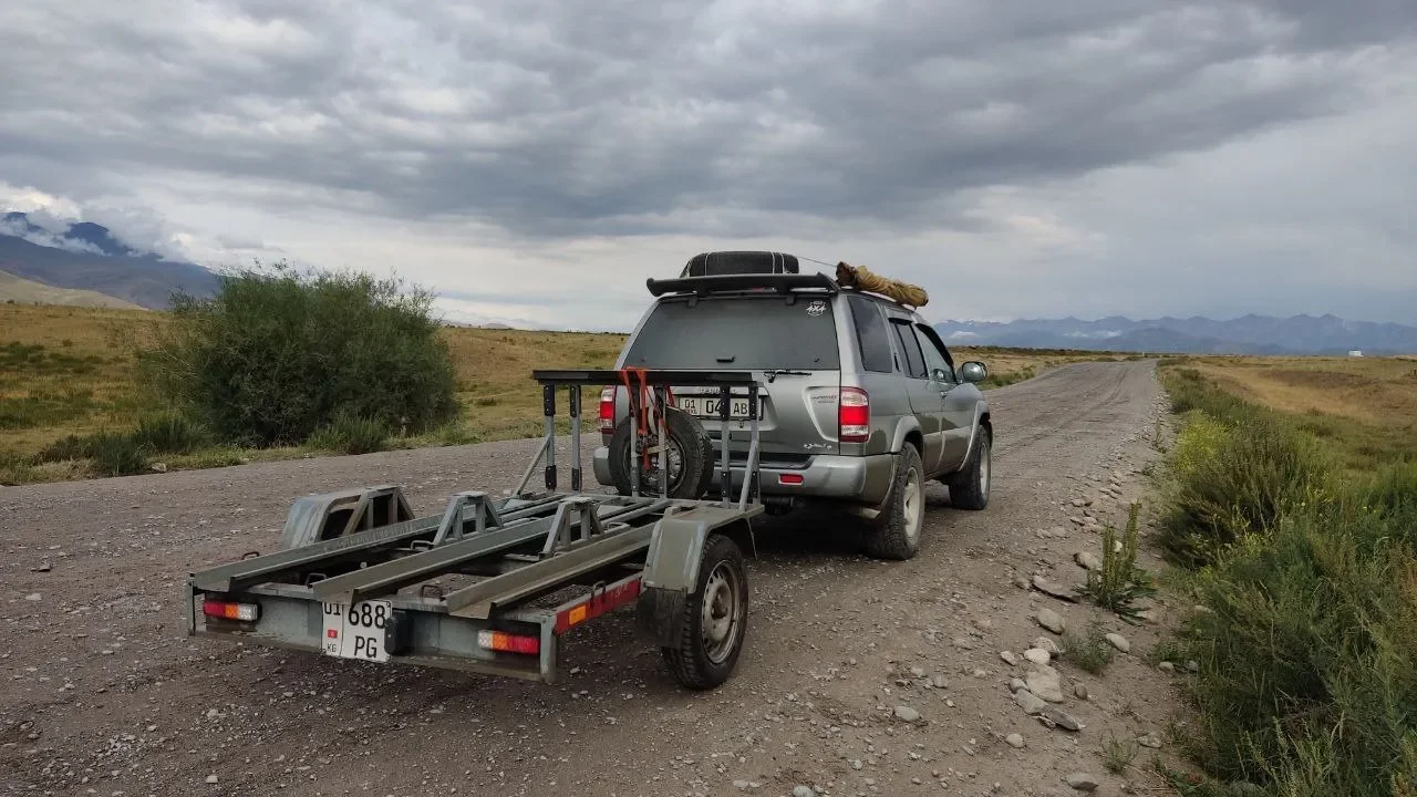 Мото-прицеп и внедорожник на степной дороге