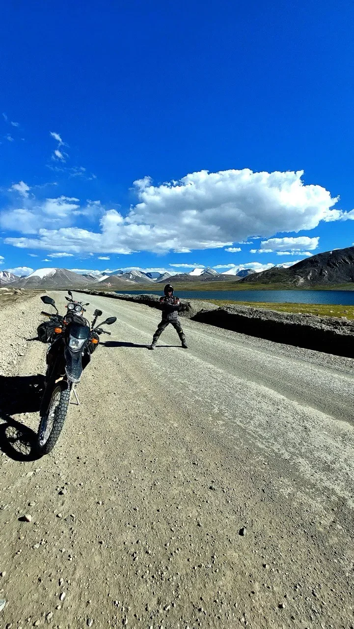 Мотоциклист у озера с панорамой гор