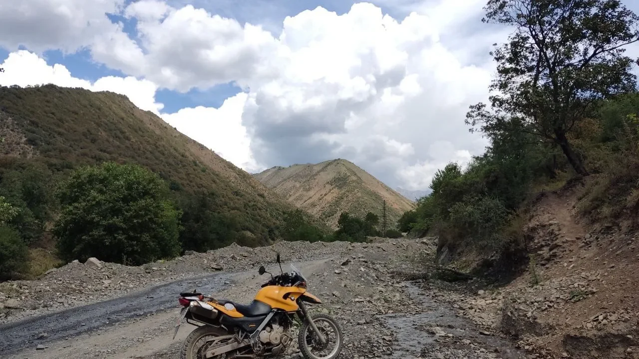 Желтый эндуро у горного ручья в ущелье