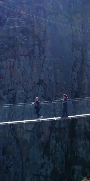 Туристы проходят по небесному мосту над пропостью
