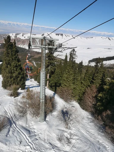 Подъемник поднимает туристов над лесом на горнолыжной базе Каракол