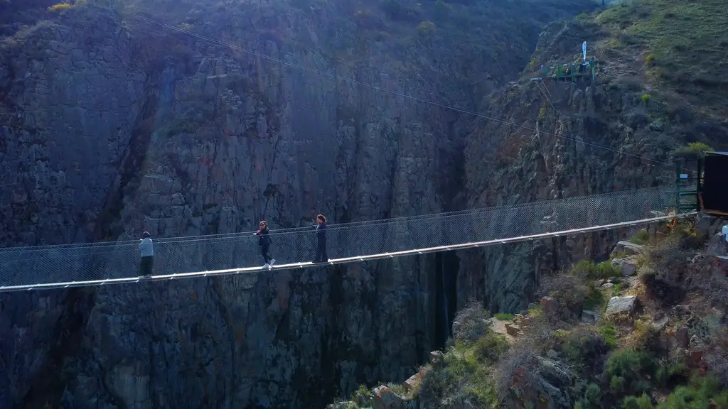 Туристы проходят по небесному мосту над пропостью